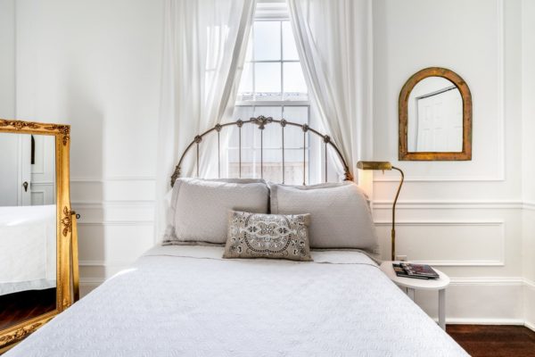 classic and comfortable white bedroom walls with golden wire frames and mirrors