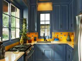 classic u-shaped kitchen with prussian blue cabinets and fire yellow ceramic backsplash