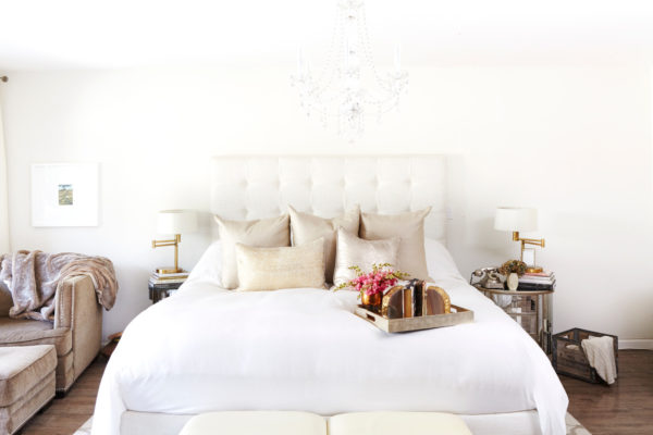 white bed and gold pillows on a dark wood floor for expensive-looking bedroom