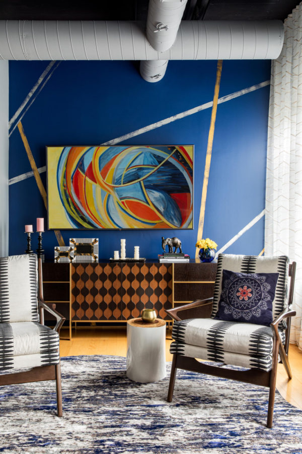 an artistic living room featuring blue accent wall and gold velvet upholstered chairs