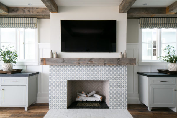 clean white tiles in front of cement mosaic fireplace, featuring beige walls and wood flooring