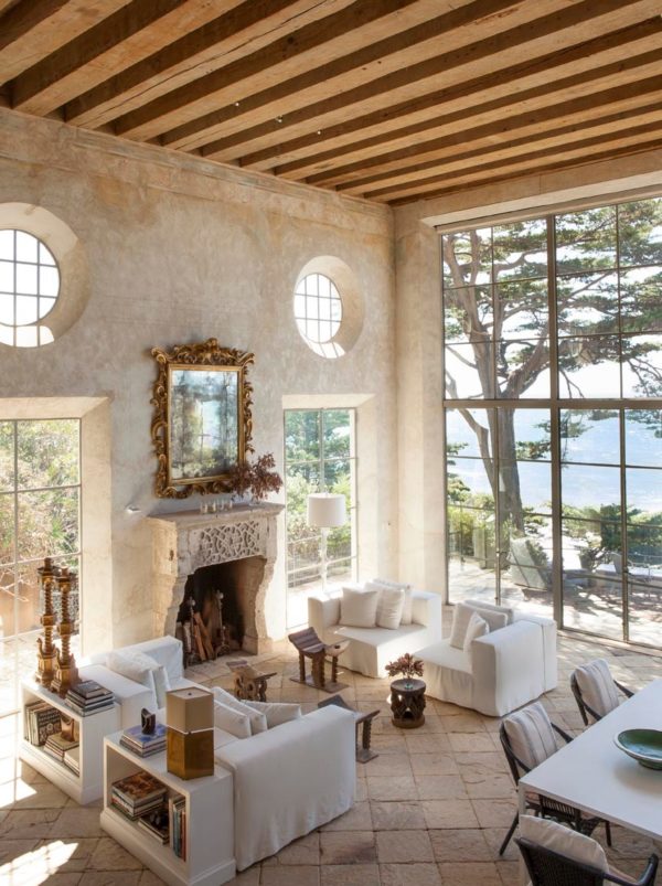 limestone tile floors in front of natural rock fireplace for a breezy, mediterranean-inspired home
