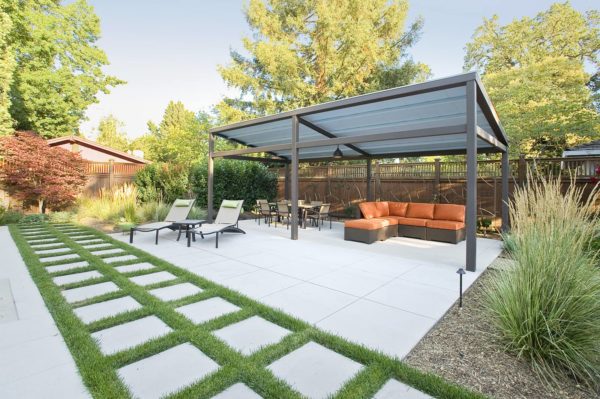 private lounging space features a concrete paver patio and classic pergola with metal roof