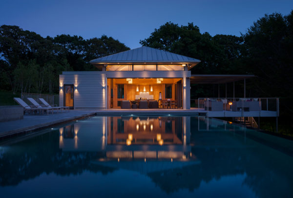 contemporary backyard and luxurious infinity pool featuring a modern pool house with bathroom