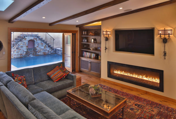 spanish-inspired mediterranean room featuring a long linear fireplace and mounted tv