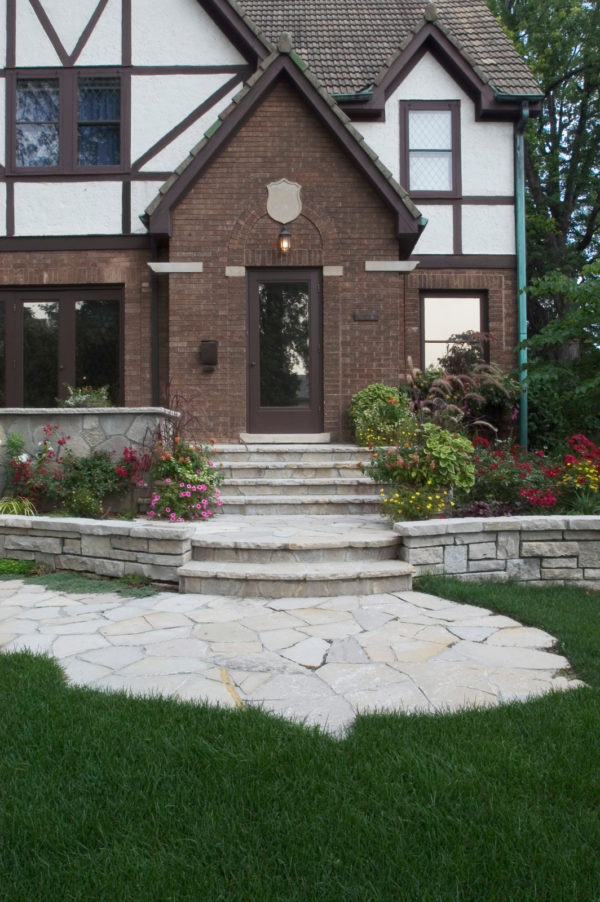an eclectic landscape with colorful flowers and flagstone masonry to complement natural retaining wall