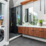 black tiled shower and hidden washing machine for an exquisite bathroom and laundry room combo