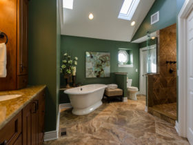 elevate a traditional bathroom with deep green walls and brown porcelain tile flooring