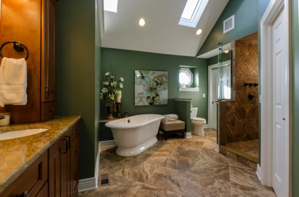 elevate a traditional bathroom with deep green walls and brown porcelain tile flooring