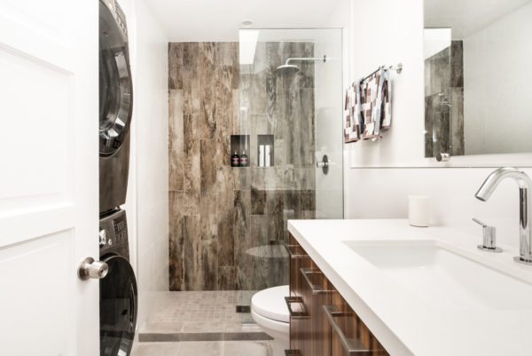 evoke luxury with quartz countertop and frameless shower door in this bathroom laundry combo