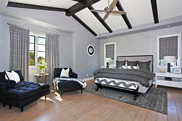 a trendy bedroom design featuring wood flooring, grey walls, and various black accents