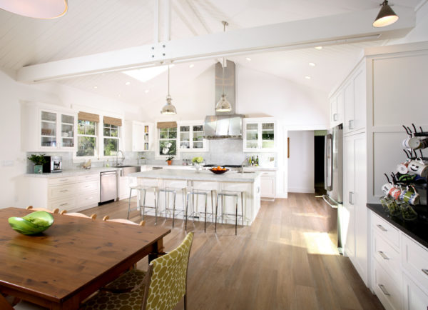 open concept kitchen and dining room with clean white walls and cozy brown floors