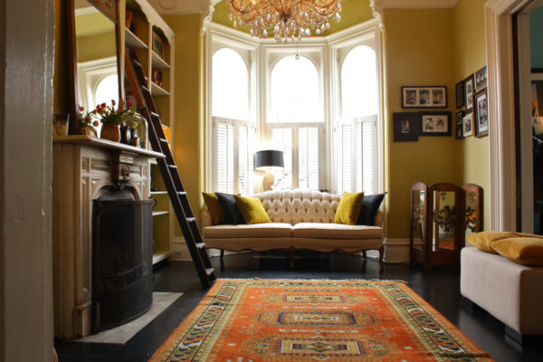 create an eclectic nook in a living room with a bay window through rustic carpet and traditional chandelier