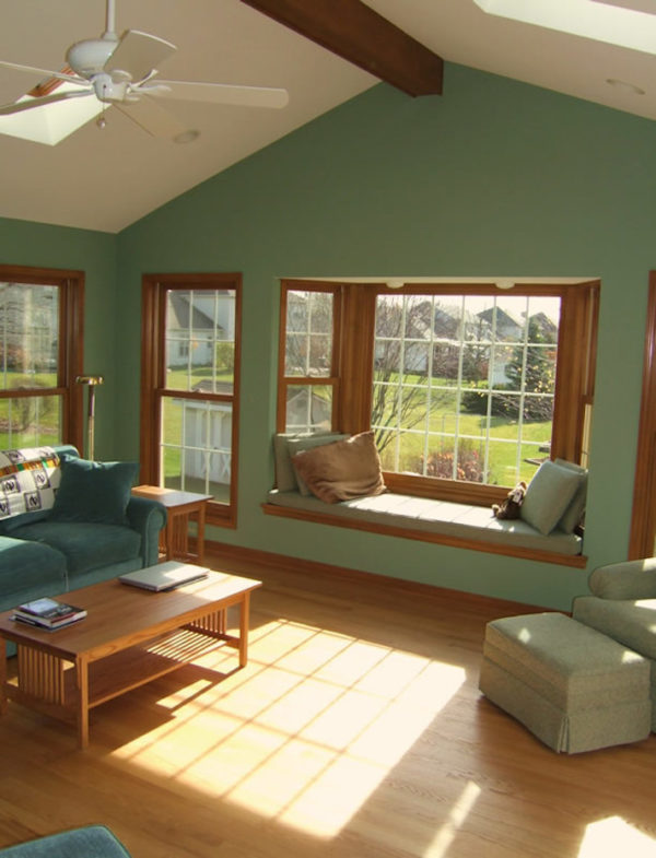 embrace a green and brown color palette in your living room with a bay window for a natural, earthy feel