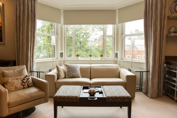 evoke modern elegance in this living room with a bay window using leather upholstery and glass tables