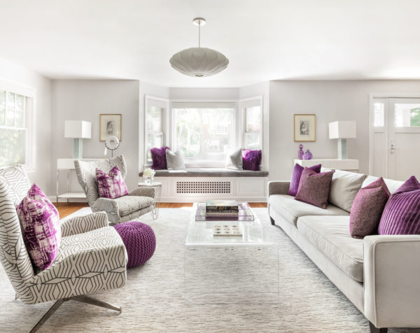 pair a white and grey living room with bright purple accents and bay window seat to invoke vogue style
