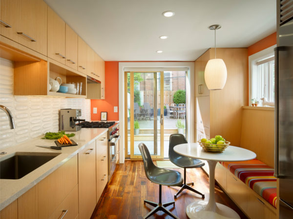 complement light brown kitchen cabinets with orange walls and sleek furnishing