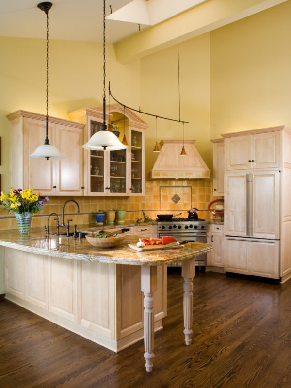 pair light brown kitchen cabinets with yellow walls and wood flooring for a cheerful, elegant vibe