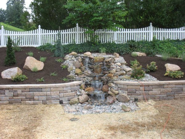 build a water feature amidst landscaping slopes with rocks for a traditional but zen ambiance