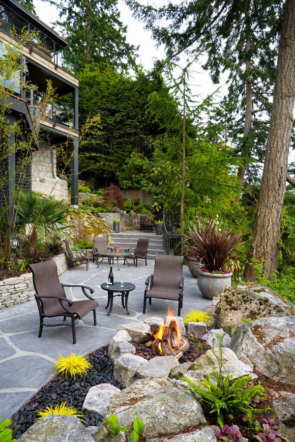 complement a retaining wall fire pit with lush greeneries to create a cool and therapeutic backyard