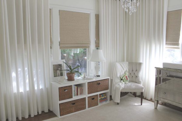 consider installing brown-toned roman shades with white curtains in a lovely all-white nursery room