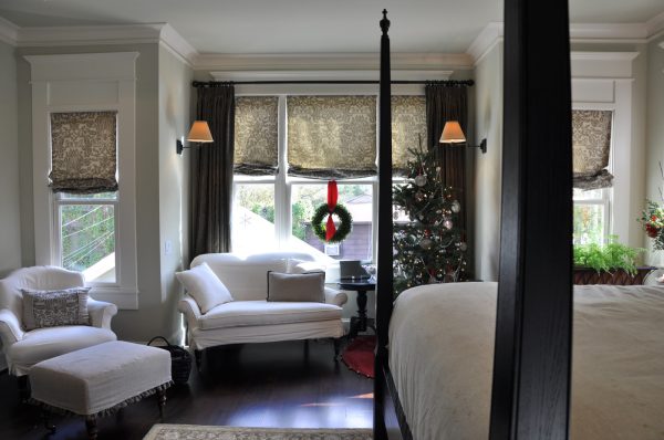 evoke the festive holiday spirit through some roman shades with curtains and an ornamented christmas tree