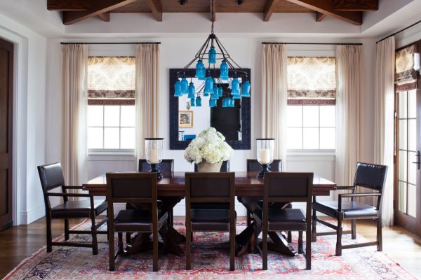 pairing blue chandeliers and patterned roman shades with curtains can convey a charming traditional feel