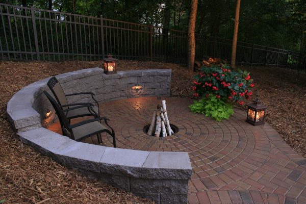 this half circle retaining wall fire pit on a brick patio evokes a homey and down-to-earth ambiance
