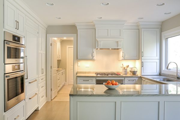 this small kitchen with peninsula pairs light wood flooring and white cabinets for a bright vibe
