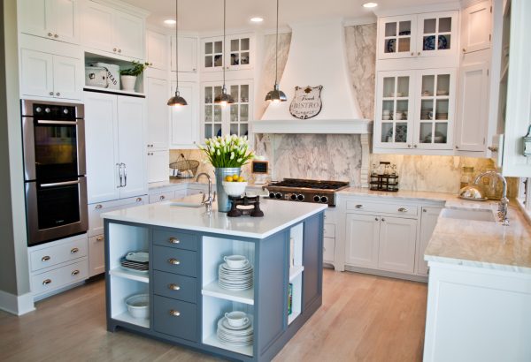 a cozy beach-style kitchen features white cabinets, white quartz countertops, and a blue island with open shelves