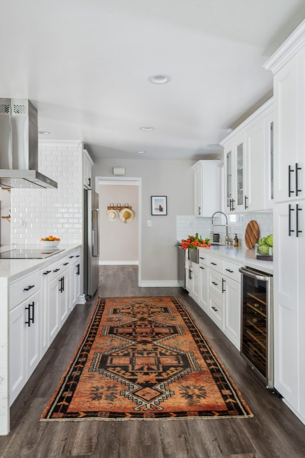 lay out a statement rug in a kitchen with white cabinets and white countertops for an intimate ambiance