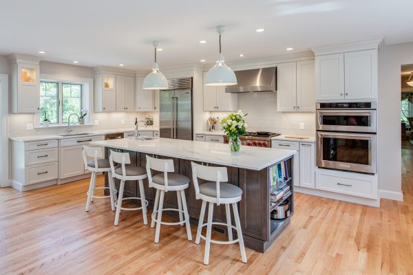 this cozy kitchen with white cabinets and white countertops features a mini bookshelf island