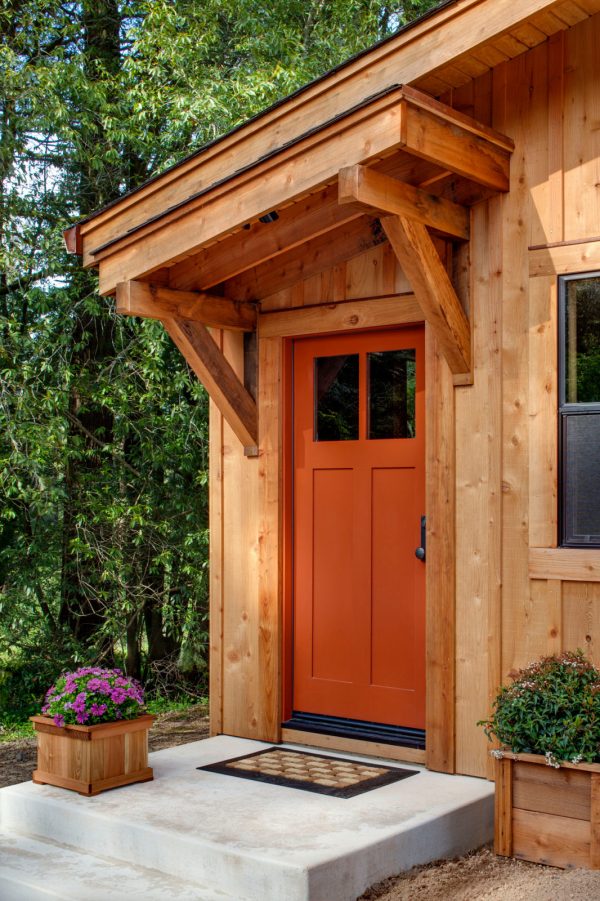 a charming barn-styled entryway with an orange front door made of premium honduran mahogany