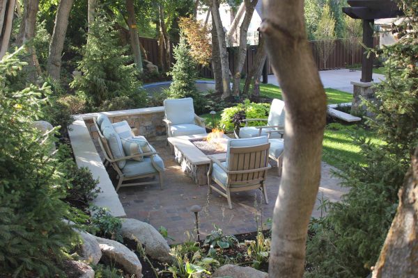 an elegant retaining wall cap that incorporates stylish furnishing and a fire pit