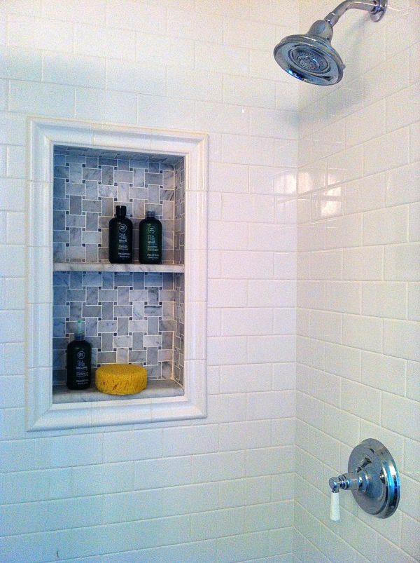 consider a country style bathroom featuring a built-in shower shelf with grey mosaic tiles