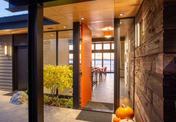 create a cozy and welcoming atmosphere using an orange front door with brown walls and black pillars