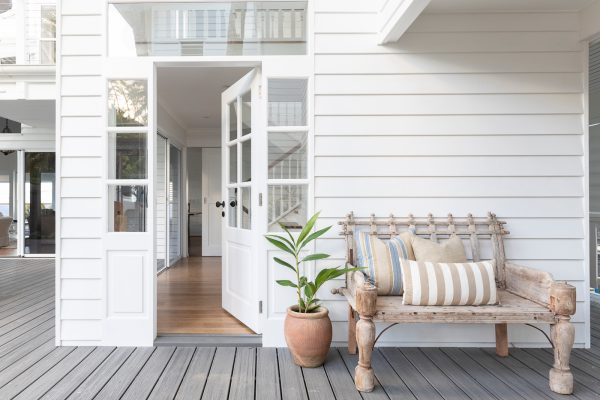 evoke tropical charm with a classic white front door and a cozy bench on the porch