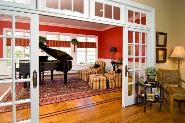 install massive white french doors with transom against red walls for an eye-catching family room