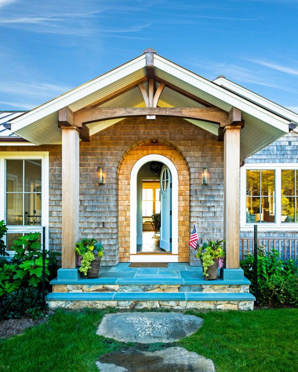 this coastal entryway with an arched white front door looks stunning under a beach style portico