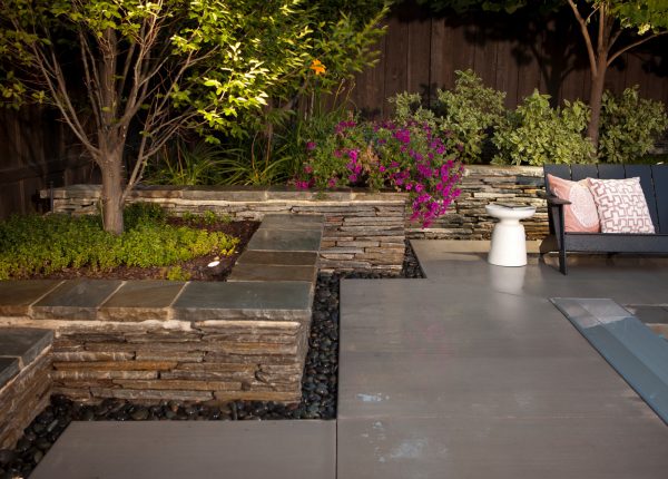 this idea of using river pebbles to enhance the bluestone retaining wall cap is perfect for a contemporary backyard