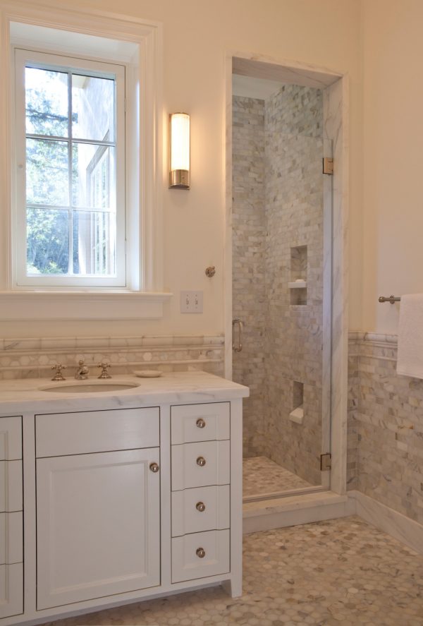 this traditional bathroom with calacatta tilework features a built-in shower shelf and toe ledge