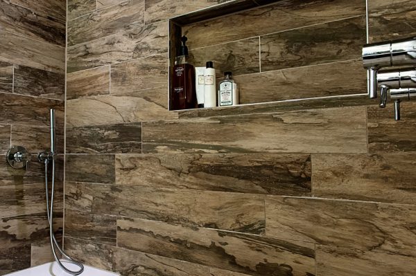 tree bark tilework makes for a lavish and stylish shower with a built-in shelf