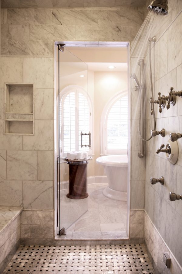 use a built-in shower shelf to maximize space amongst carrera marble tiles in this classic bathroom