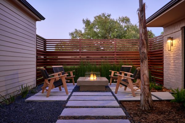 the glass-walled fire pit creates a lovely focal point for a small backyard and no grass