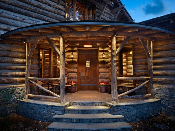 this antique log cabin front door looks cozy and rustic with additional seating