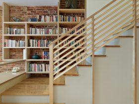 this indoor diagonal wood stair railing design features a mini library for a dramatic entryway