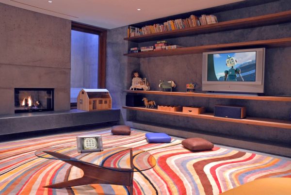 this modern family room features a fun pattern multi-colored carpet and dark gray wall color combination