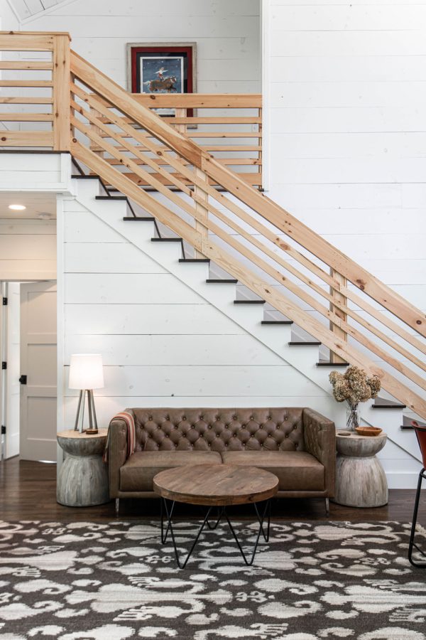 this rustic indoor horizontal wood stair railing design contrasts the shiplap wall and modern living room
