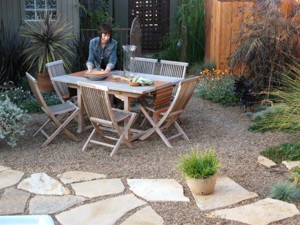 this small backyard with no grass features a dining table atop cameron flagstone and pea gravel