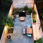this small backyard with no grass uses bluestone pavers and wood walls for a trendy city garden